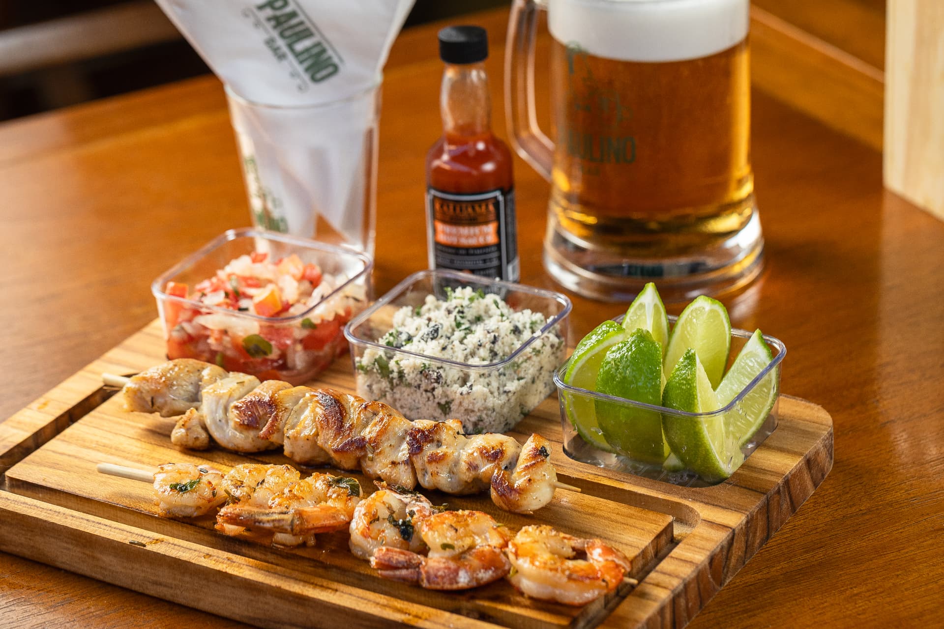 Tábua com espetinhos de frango e camarão, vinagrete, farofa e limão com chopp do Paulino