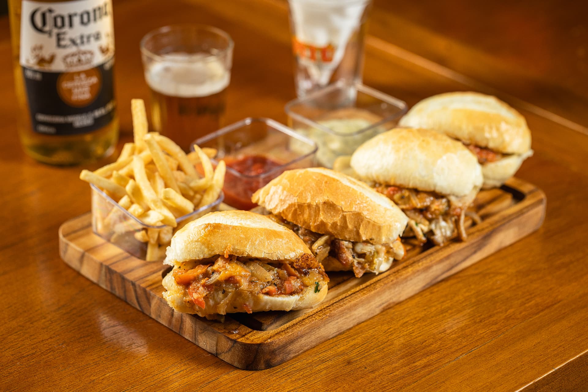 Trio de sanduíches de pernil com fritas e cerveja gelada